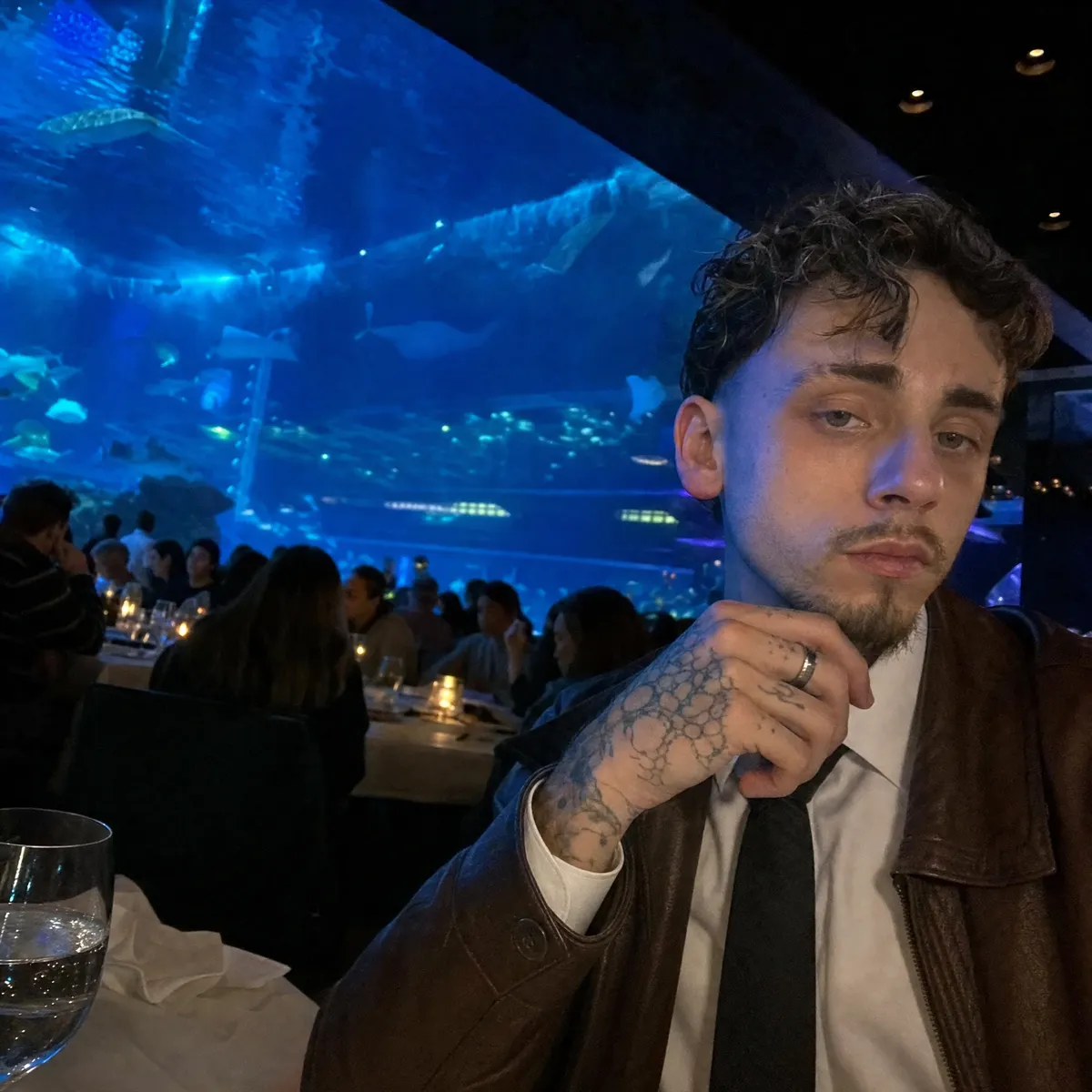 Le fondateur attablé dans un restaurant, devant un mur d'aquarium